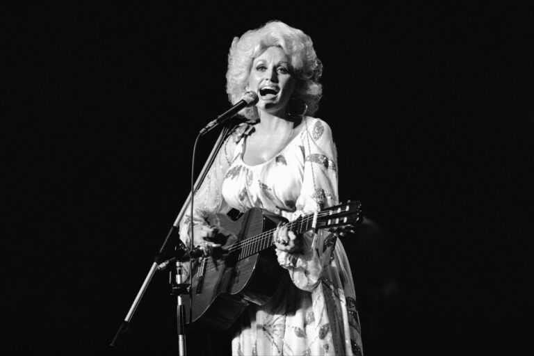 Dolly Parton is singing and playing guitar on stage in Tokyo in 1979.