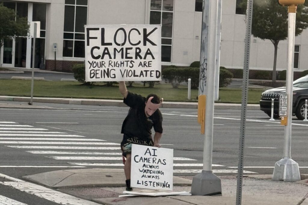 flock-protest-signs-millcreek-delaware-2026-cropped-pe Joshua Pyle se manifiesta en la autopista Kirkwood, en Millcreek