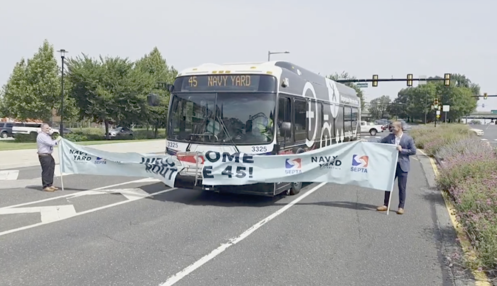 A SEPTA bus breaks through a ceremonial banner as it travels into the Navy Yard for the first time.