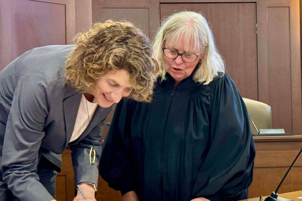 suzanne-goode-delaware Suzanne Goode signing paper next to a judge