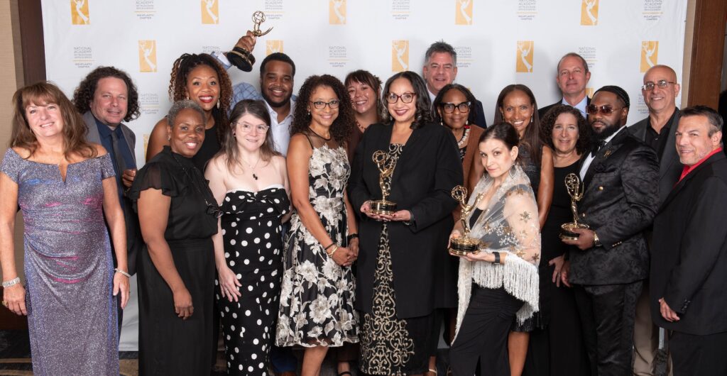 01 WHYY-2026 Emmys A large group photo showing WHYY staff members holding up the statuettes they received for winning many Mid-Atlantic Regional Emmy Awards.