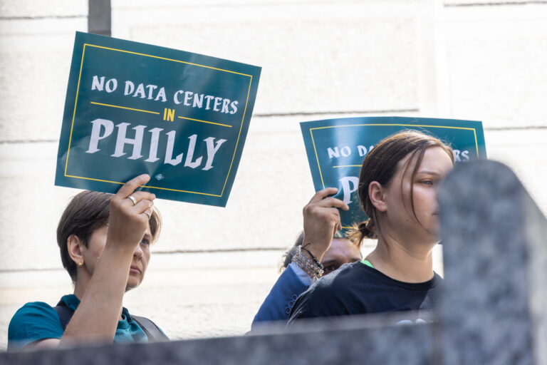 two people hold signs reading NO DATA CENTERS IN PHILLY