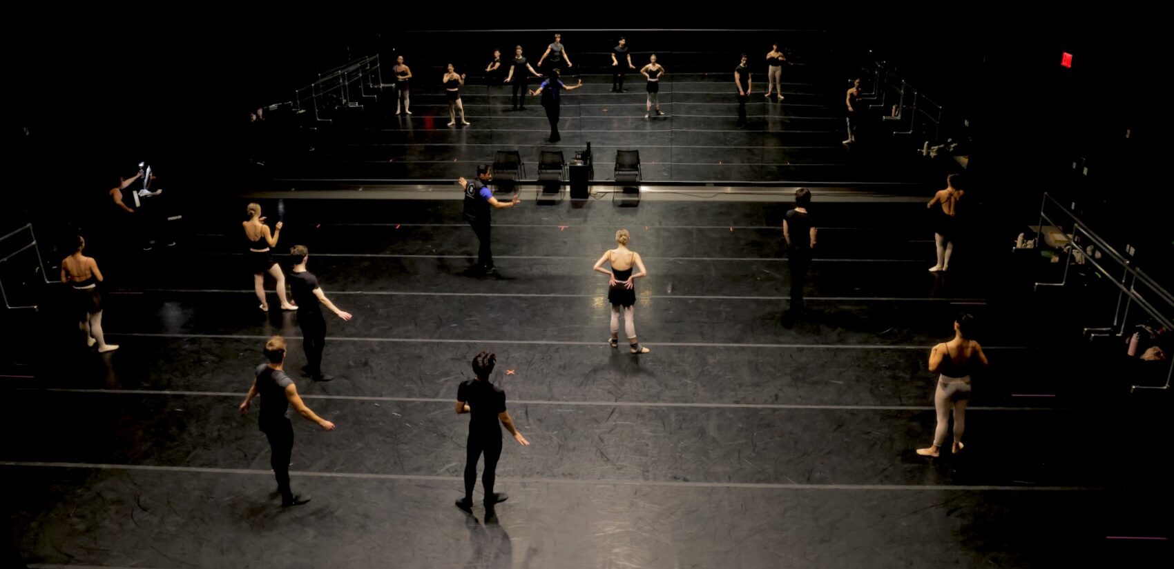 A view from above as dancers rehearse in a black box theater.