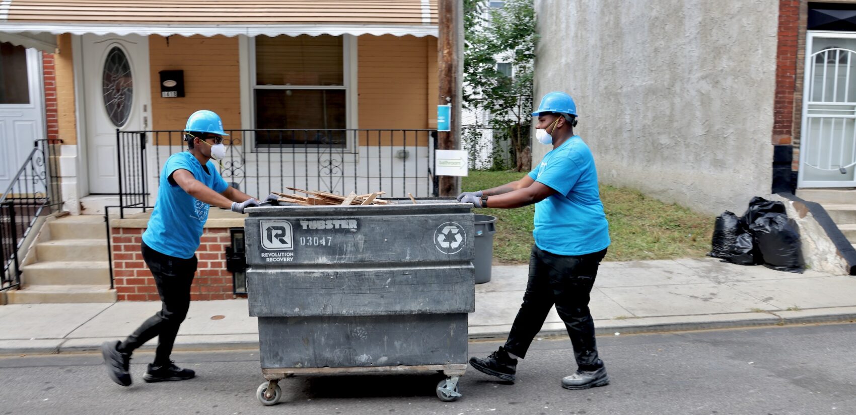 High school students Jeremayah Maneiro and Kendal Moffitt clear debris from a home under renovation