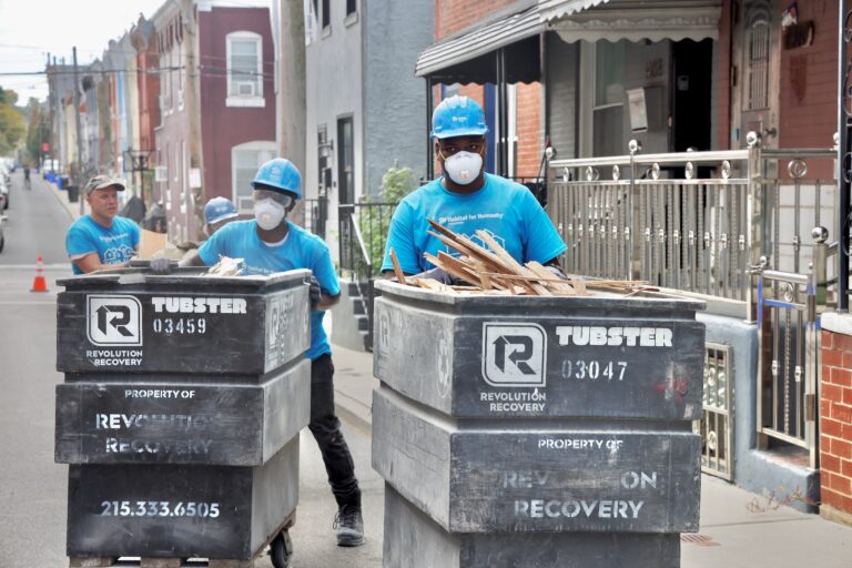 Kendal Moffit, 17 (right), clears debris from a house on North Holywood Street in Brewerytown