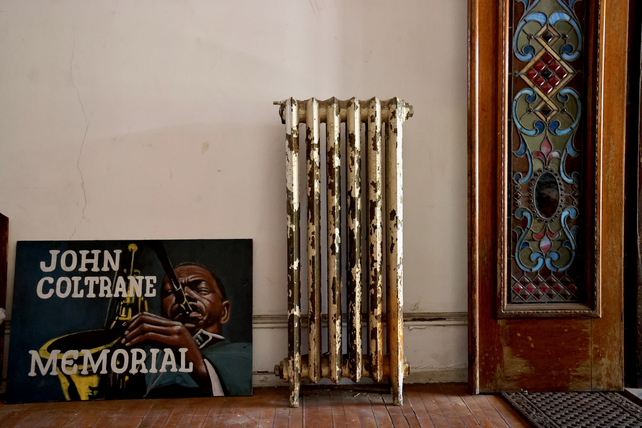 a grate for a radiator by a sign that reads JOHN COLTRANE MEMORIAL