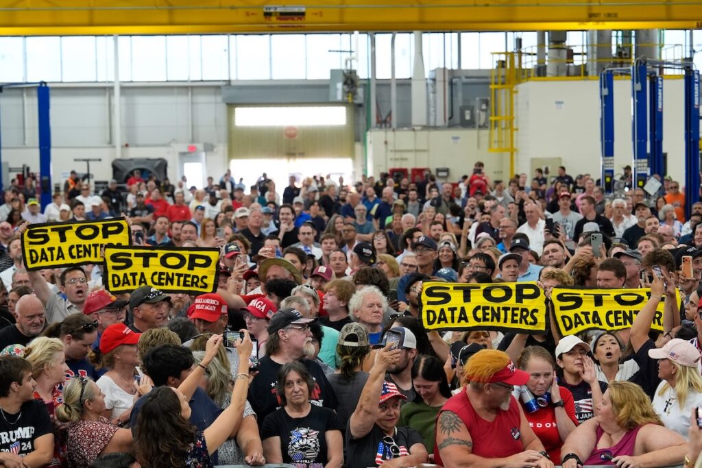 Trump People wait for President Donald Trump to arrive at an event at the General Motors Proving Ground Monday, July 27, 2026, in Milford, Mich. (AP Photo/Paul Sancya)