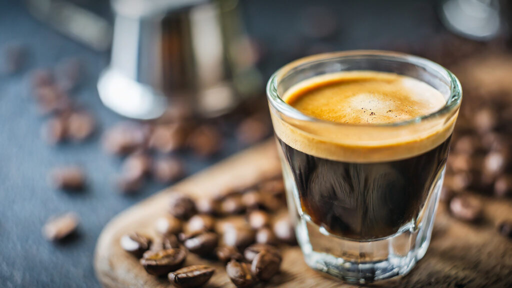 A cup of coffee surrounded by coffee beans