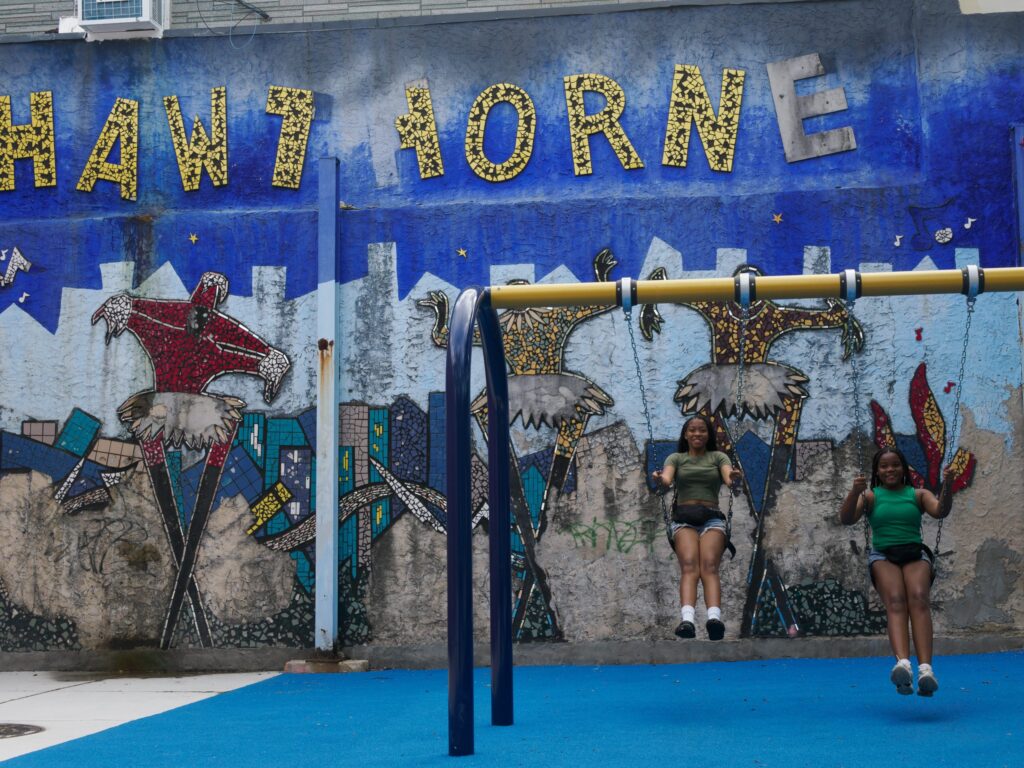 Naziyaa and Peyton swing past the Hawthorne Cultural Center's mosaic mural,