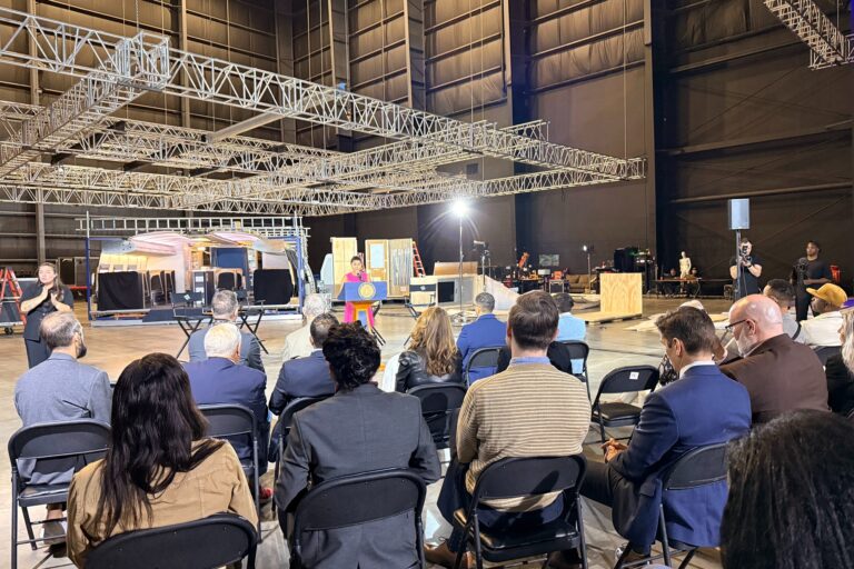 a group of people sit at the event while a presenter speaks