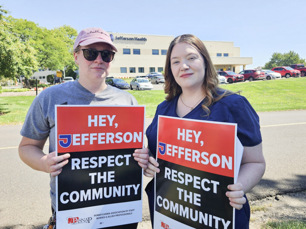 Two people hold signs reading HEY, JEFFERSON RESPECT THE COMMUNITY