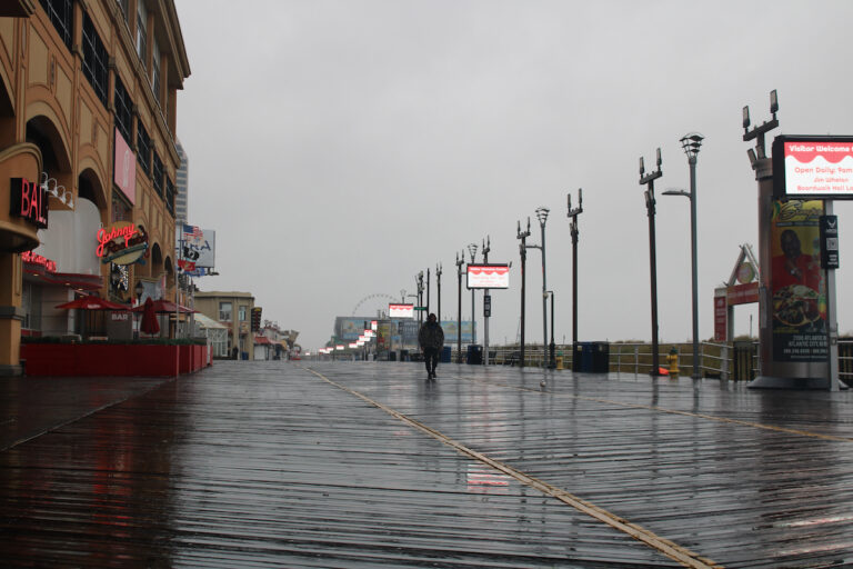 A single person walks in the Atlantic City Boardwalk while wearing a rain jacket during a nor'easter storm
