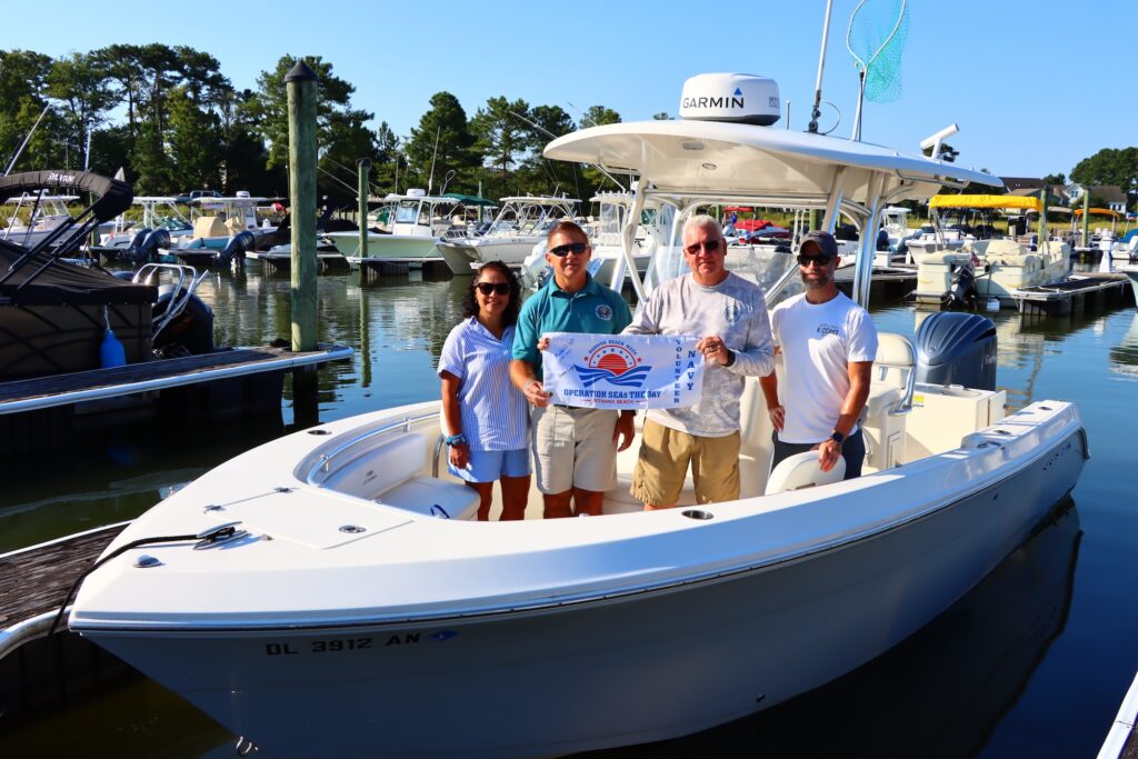 operation-seas-2026-09-04-1 A group of people are posing for a photo in their speedboat and holding an Operation Seas the day banner.