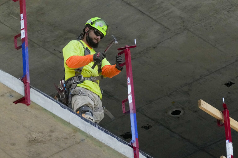 A construction worker installs a safety railing on a new building in Philadelphia