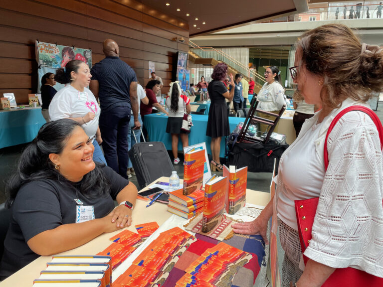 A book author speaks speaks to a woman at a book fair