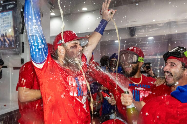 Philadelphia Phillies first baseman Bryce Harper, left, is doused by Garret Stubbs, right, during a celebration in the clubhouse after the team clinched a Wild Card slot in the postseason by defeating the Tampa Bay Rays in a baseball game Sunday, Sept. 27, 2026, in Philadelphia.