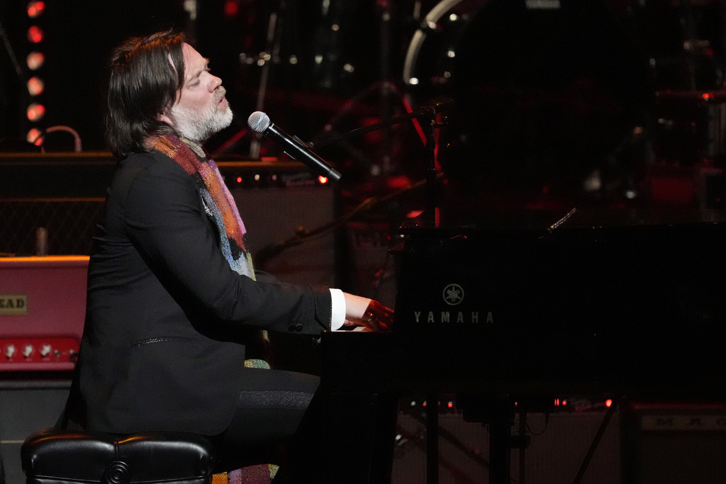 Rufus Wainwright plays a piano and sings into a microphone