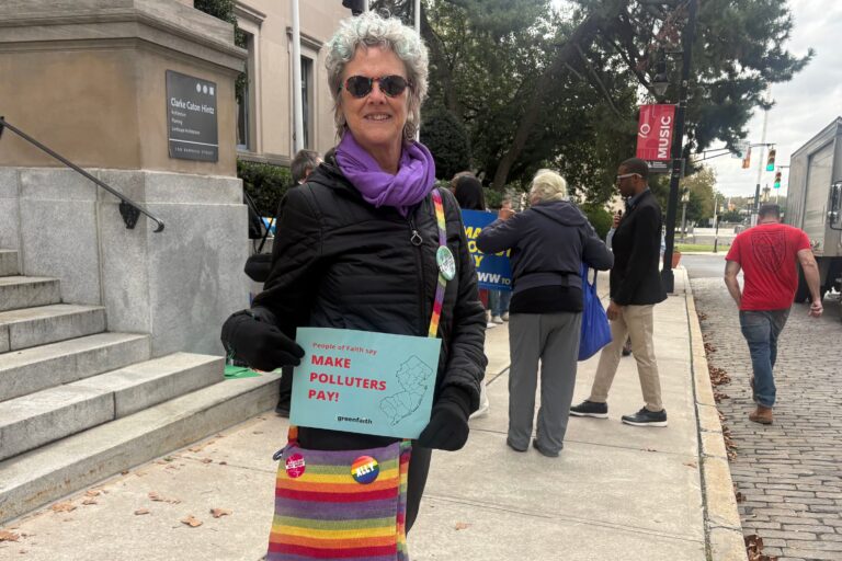 Tracey Stephens holds a sign reading People of Faith say MAKE POLLUTERS PAY!