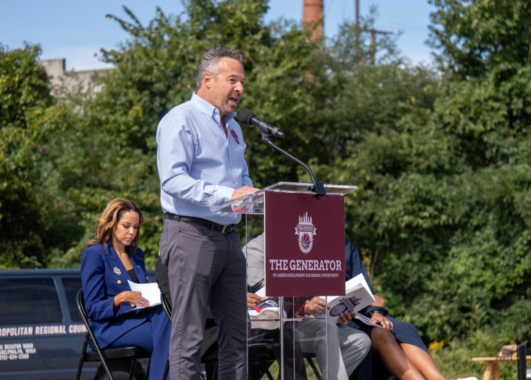 Philadelphia Youth Basketball CEO and co-founder Kenny Holdsman speaks into a microphone at a podium