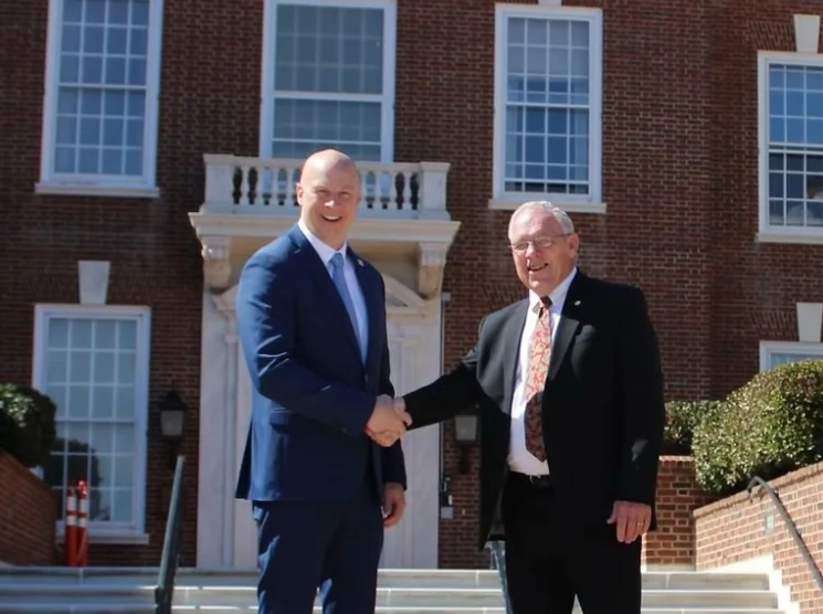 Doug Conaway is shaking hands with Rich Collins in front of Legislative Hall.