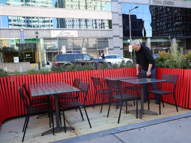 three tables with chairs in the street off the sidewalk by LOVE Park