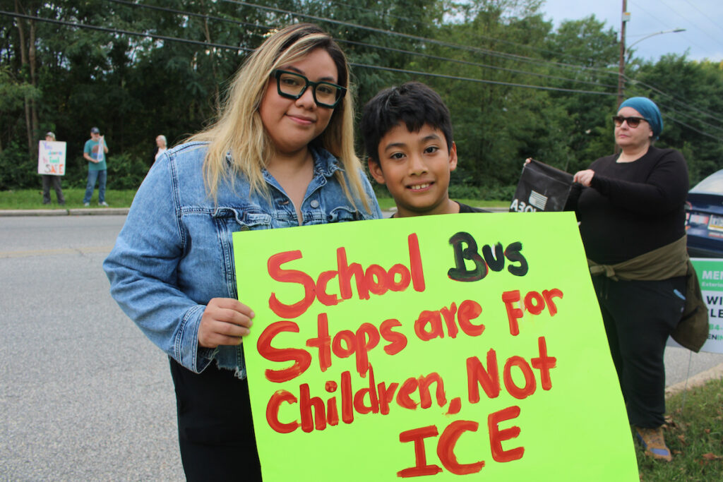 Rose De La Luz and Leon Garces De La Luz are holding up a sign that says 'School bus stops are for children, not ICE,' while at an anti-ICE protest in Norristown, Pa.