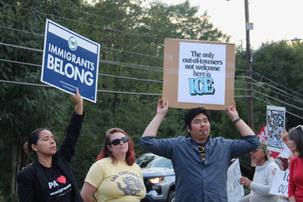 Several people are shown holding up handmade signs while standing on the side of the road for the anti-ICE protest in Norristown.