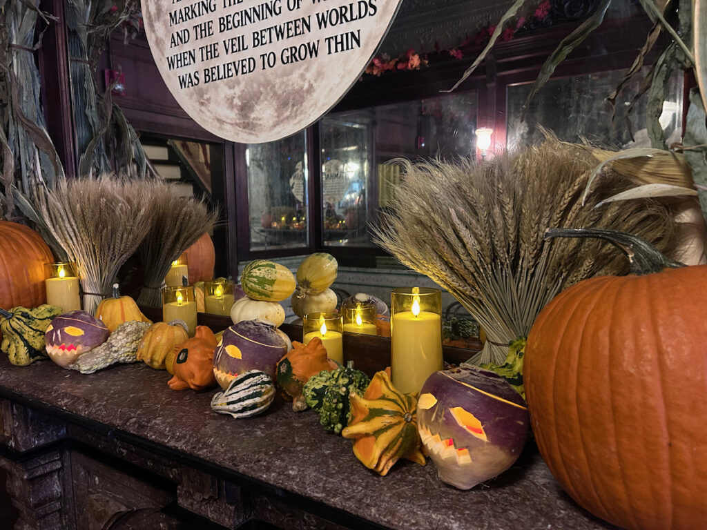 samhain – 2 Pumpkins and jack-o-lanterns sit on top of a fireplace for a Sanheim celebration