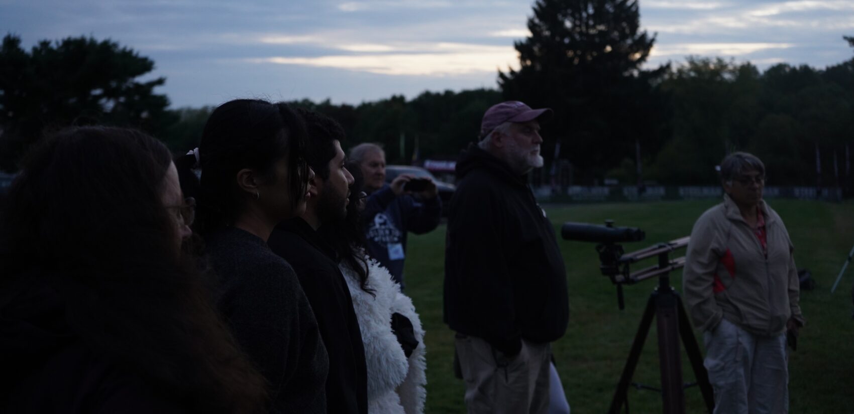 People watch a science demonstration with a telescope visible