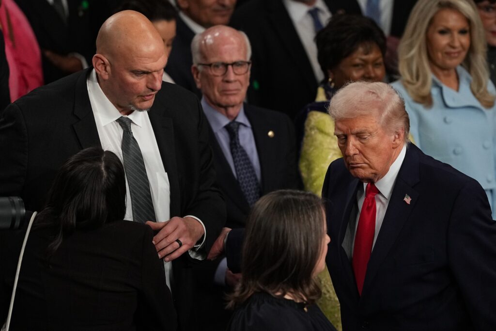 Trump Fetterman Donald Trump is walking by John Fetterman, who is standing up after Trump completed his State of the Union address in Feb. 2026.
